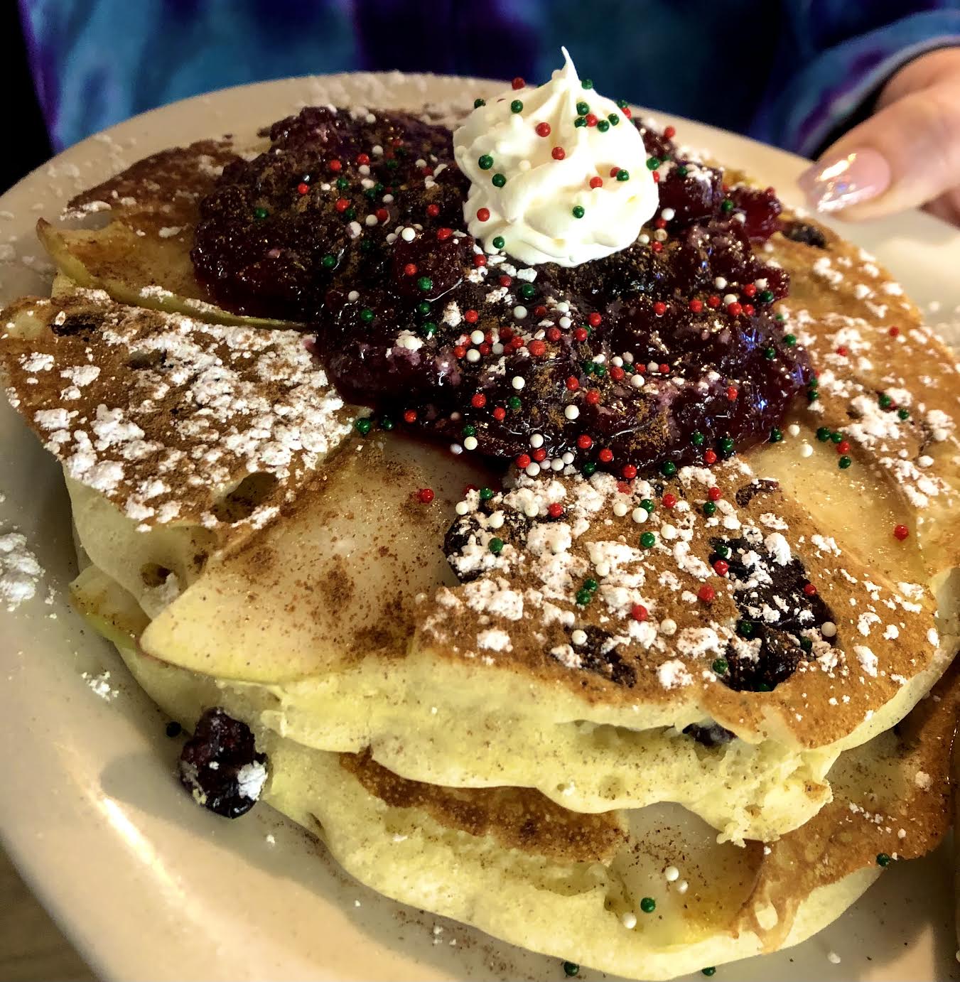 A stack of pancakes topped with blueberries and powdered sugar at Herb’s